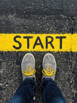 Person Standing at the Start Line on Asphalt Road with Yellow Paint, Concept of Beginning and Motivation
