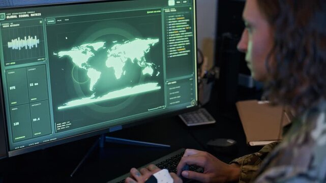 Young adult Caucasian female soldier typing on keyboard while monitoring global map on computer screen in military command center. Perfect for cybersecurity and defense technology videos