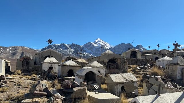 Cemit&eacute;rio hist&oacute;rico de Milluni com o pico nevado Huayna Potos&iacute; ao fundo, Bol&iacute;via. V&iacute;deo vertical de tumbas r&uacute;sticas e cruzes no altiplano andino sob c&eacute;u azul.
