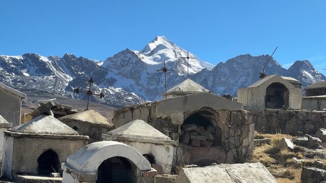 Cemit&eacute;rio hist&oacute;rico de Milluni com o pico nevado Huayna Potos&iacute; ao fundo, Bol&iacute;via. V&iacute;deo vertical de tumbas r&uacute;sticas e cruzes no altiplano andino sob c&eacute;u azul.