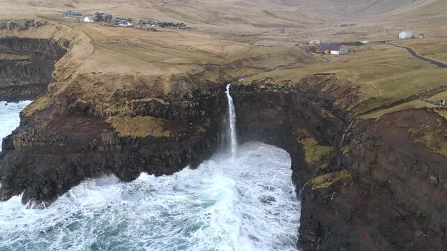 フェロー諸島ガーサダルル、断崖から海へ落ちるムーラフォッサー滝を空撮（Faroe Islands Gasadalur Mulafossur Waterfall Aerial 4K）