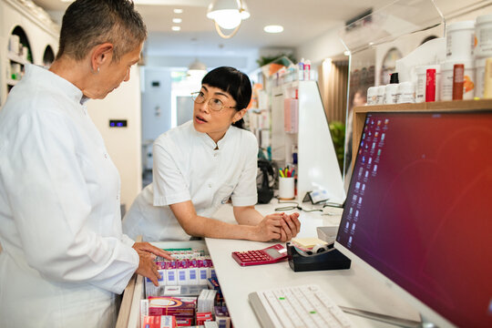 Pharmacists discussing medication inventory at pharmacy counter