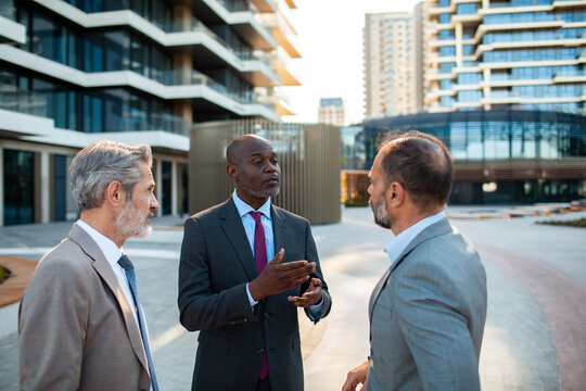 Business executives discussing project outside modern office buildings