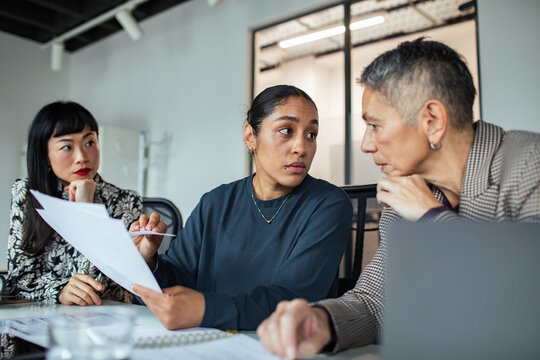 Three businesswomen discussing documents in modern office