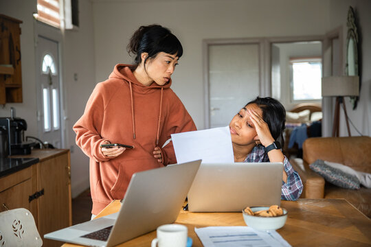 Two women stressed over household bills with laptops at home