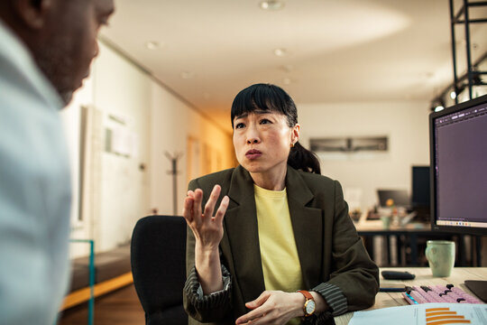 Concerned businesswoman discussing project with colleague in modern office