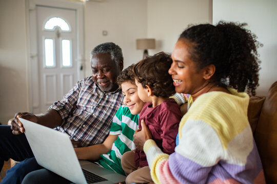 Grandfather, mother and children video chatting on laptop at home