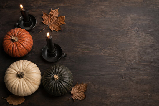 Elegant Halloween flat lay with pumpkins and black candles