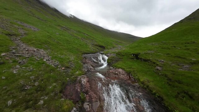 Aerial FPV along cascading river in Scottish highlands Glencoe Skye