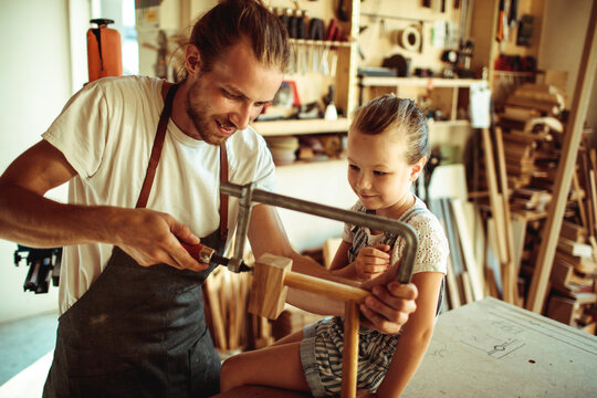 Father and daughter woodworking together in carpentry workshop