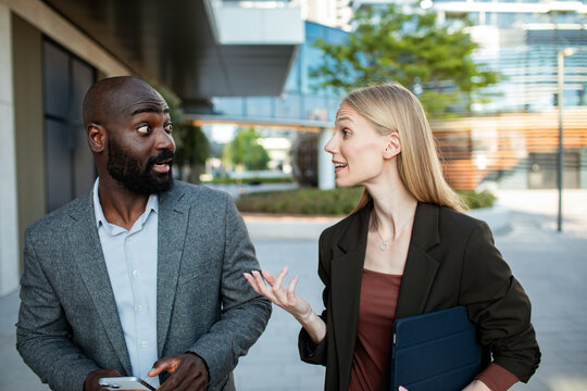 Two coworkers discussing project while walking outside modern office