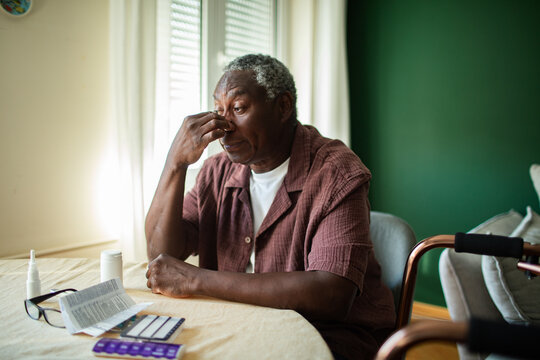 Senior man with headache at home table with medications
