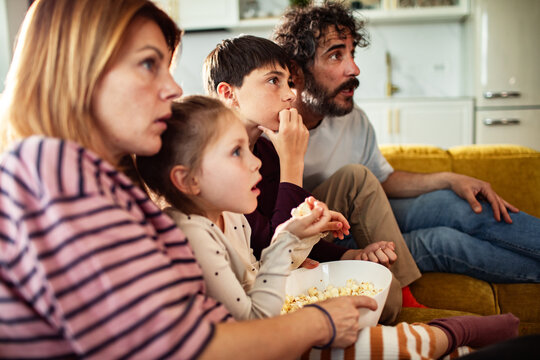 Family watching movie with popcorn at home