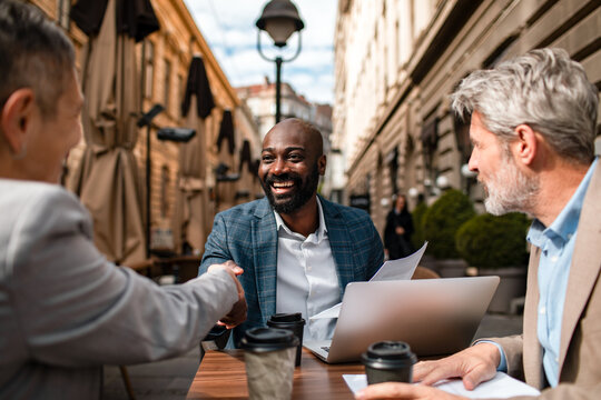 Business professionals shaking hands at outdoor cafe meeting