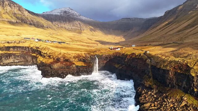 フェロー諸島ヴァーガル島、断崖から海へ落ちるムーラフォッスルの滝と village を空撮（Faroe Islands Mulafossur Waterfall Aerial 4K）