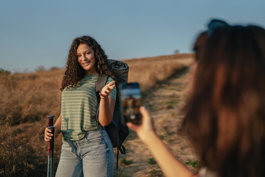 Friends hiking and taking smartphone photos outdoors