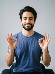 Naklejka premium Young Handsome Man Meditating with Eyes Closed and Mudra Hand Gesture for Mindfulness and Stress Relief