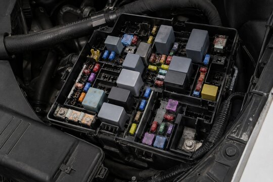 Open vehicle fuse box with color-coded blade fuses and relays in engine bay