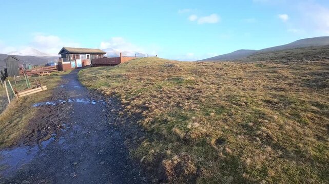 フェロー諸島の丘に建つ小屋と牧草地、遠くの村とフィヨルドを望む（Faroe Islands Hillside Hut and Pasture with Fjord View）