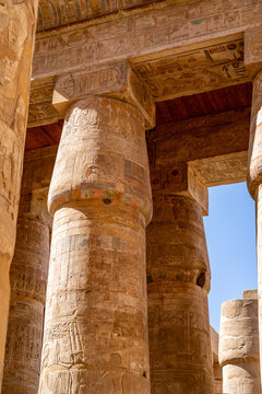 Intricate Hieroglyphics Carved into Ancient Stone Columns at Medinet Habu Temple Complex in Luxor, Egypt, Featuring Historical Architecture and Faded Colors under Bright Sun