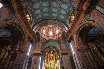 Naklejka premium Gilded interior of the historic Church of La Compañía de Jesús (Iglesia de la Compañía de Jesús), showing the ornate gold leaf altarpiece, vaulted Mudéjar ceiling, and cupola in Quito, Ecuador.