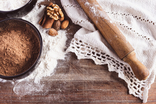 A top-down view of freshly baked ingredients laid out on a linen cloth, a bowl of flour, and a rolling pin, ready for making homemade pastries and comforting recipes.