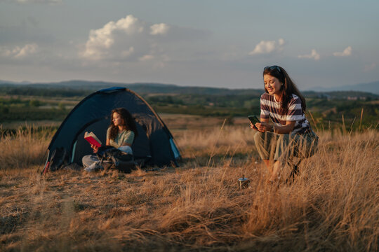 Women camping and relaxing in nature at sunset