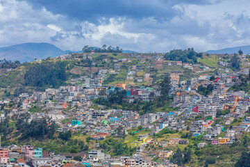 Fototapeta premium Colorful colorful houses and dense residential buildings built on the hillside slopes in Quito, Ecuador, against Andean mountain background.