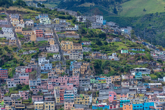Colorful colorful houses and dense residential buildings built on the hillside slopes in Quito, Ecuador, against Andean mountain background.