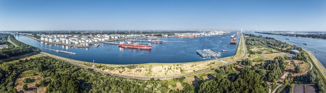 Aerial panorama of Rotterdam port with container ship and wind turbines