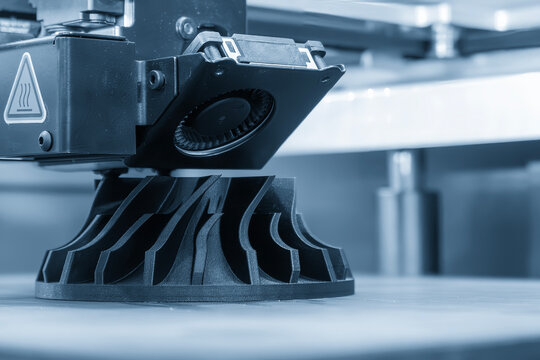 Additive manufacturing process on 3D printing machine in dramatic blue tone lighting