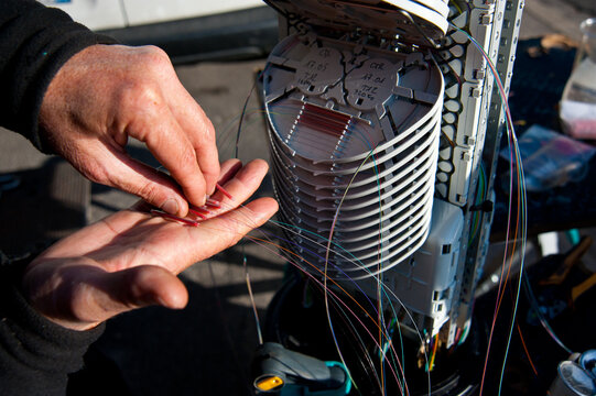 Technician hands installing fiber optic telecommunications cables