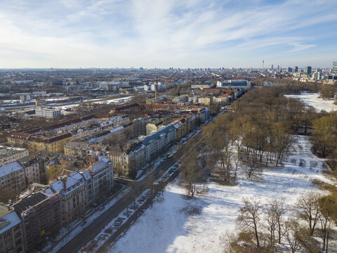 Aerial view of the city of Berlin in winter, featuring snow-covered parkland, urban residential buildings, and a clear blue sky in Berlin, Berlin, Germany.