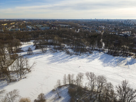 Aerial view of a snow-covered park with bare trees and long shadows in Berlin, Berlin, Germany.
