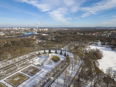 Aerial view of the Soviet War Memorial in Tiergarten surrounded by snow-covered trees and parkland under a clear blue sky in Berlin, Berlin, Germany.