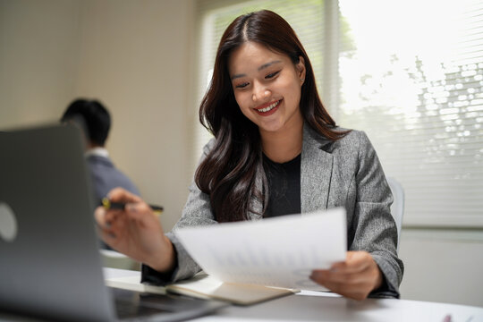 Woman analyzing business documents and working remotely with laptop for office productivity and business presentation