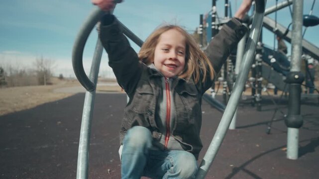 Boy climbing curved metal arch bars at modern playground from behind