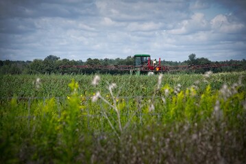 Farm tractor spraying crops in a green field © dslr-user61