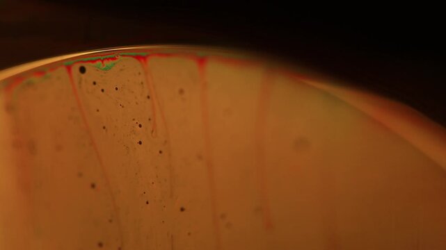 Golden amber fluid dome edge with micro droplets and warm gradient backlight. A low-key macro shot capturing the curved upper horizon of a liquid dome. Smooth background 
