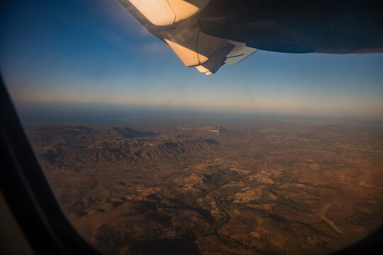 Aerial view of rugged mountainous landscape and dry terrain seen from an airplane window during a flight over Madagascar.
