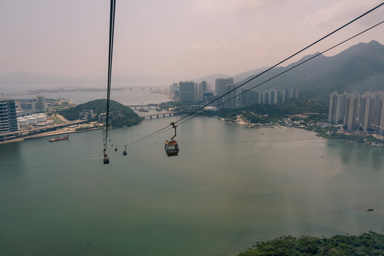 Aerial view from a Ngong Ping 360 cable car cabin over Tung Chung Bay and dense residential neighborhoods in Tung Chung on Lantau Island, Hong Kong - 27 August 2026.