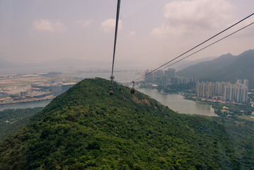 Aerial view from a Ngong Ping 360 cable car cabin over Tung Chung Bay and dense residential neighborhoods in Tung Chung on Lantau Island, Hong Kong - 27 August 2026. © IBRESTER