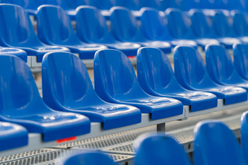 Fototapeta premium Vibrant blue bleacher seats stand ready for cheering crowds during an exciting sports event at a bustling stadium