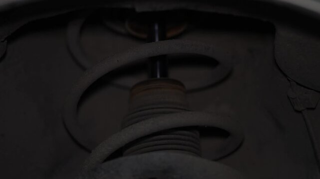 Close up shot of dusty car suspension coil spring strut.
