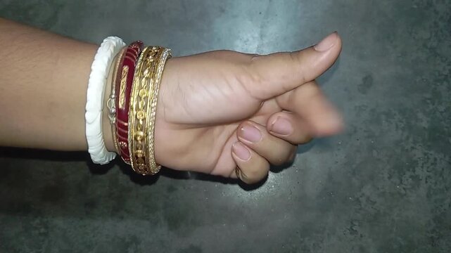 Close up of woman wearing traditional Indian bangles pointing index finger and showing hand gestures on concrete background