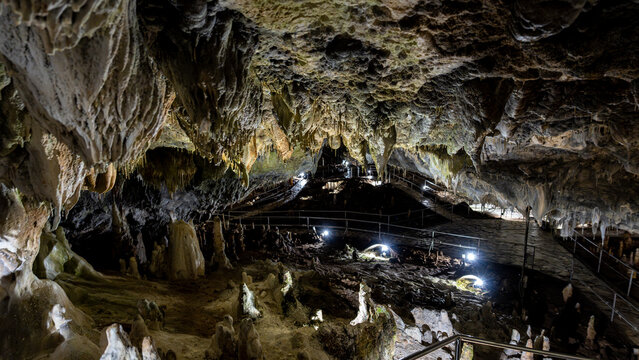 Illuminated limestone cave with stalactites and walkway
