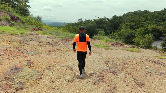 Drone view of man trail running through the mountains. The extreme outdoor sport represents endurance and personal challenge while pursuing fitness goals, achievement and an active healthy lifestyle.
