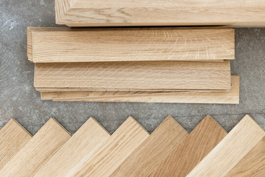 Beige parquet planks on concrete floor during herringbone hardwood flooring installation