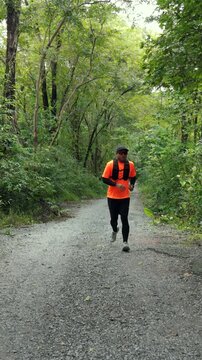 Drone view of man trail running through a mountain forest. Extreme outdoor sport represents endurance and personal challenge while pursuing fitness goals, achievement and a healthy active lifestyle.
