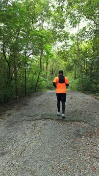 Drone view of man trail running through a mountain forest. Extreme outdoor sport represents endurance and personal challenge while pursuing fitness goals, achievement and a healthy active lifestyle.
